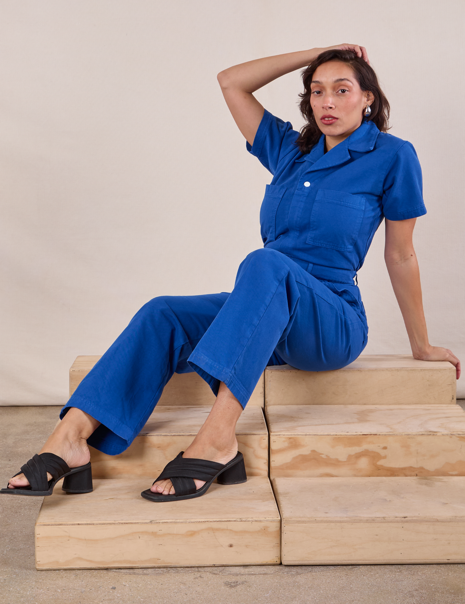 Short Sleeve Jumpsuit in Royal Blue worn by Tiara sitting on a wooden crate