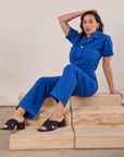 Short Sleeve Jumpsuit in Royal Blue worn by Tiara sitting on a wooden crate