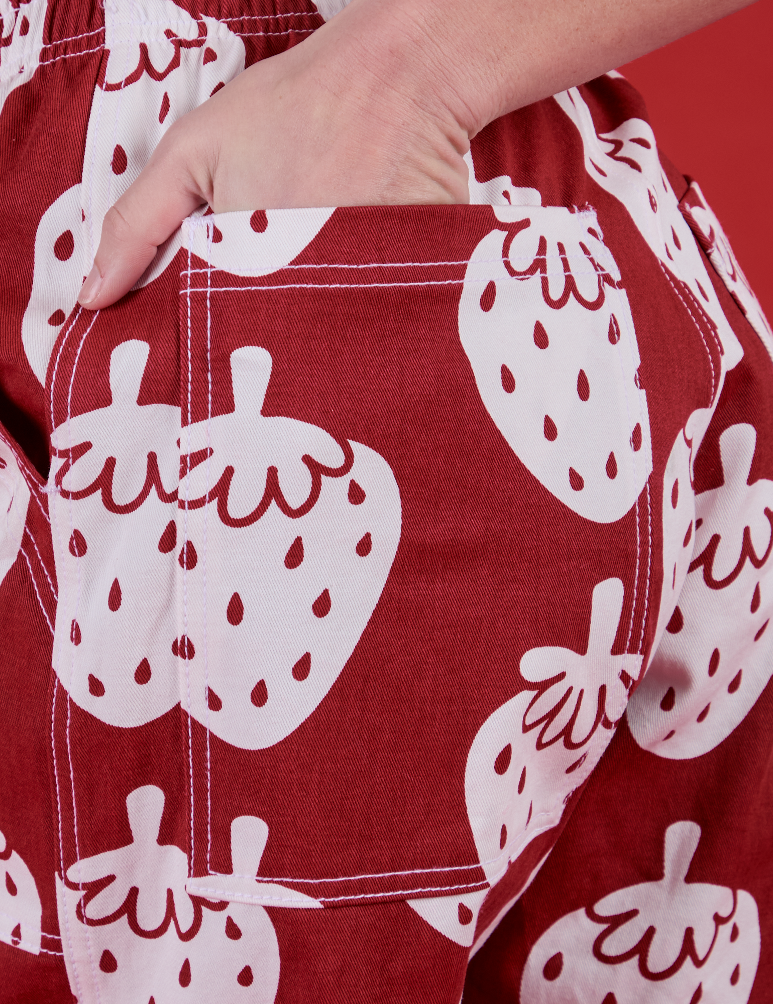 Close up of Alex's hand in the back pocket of Drop Pocket Pants in Strawbaby