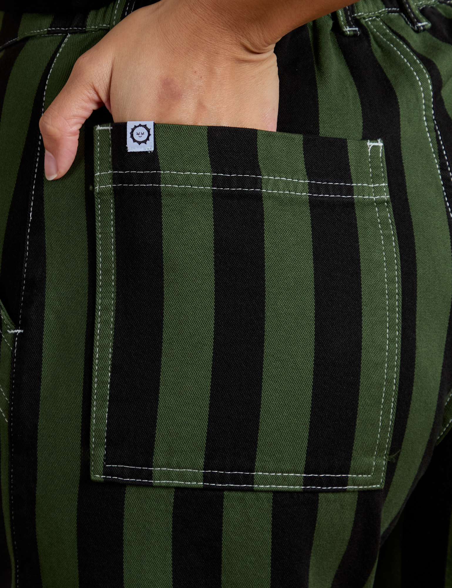 Close up of Tiara's hand in the back pocket of Black Stripe Work Pants in Evergreen