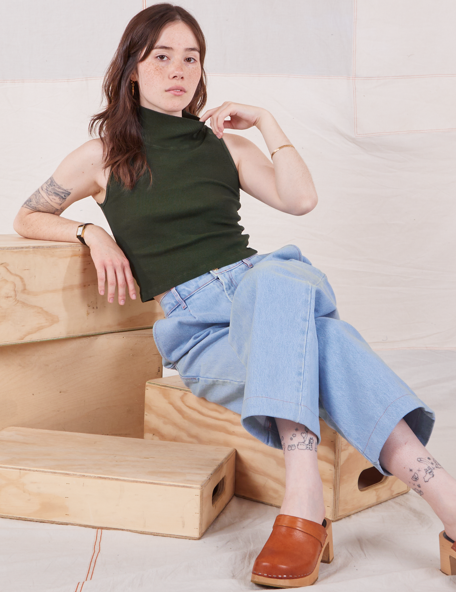 Hana is wearing Sleeveless Essential Turtleneck in Swamp Green and light wash Denim Trouser Jeans