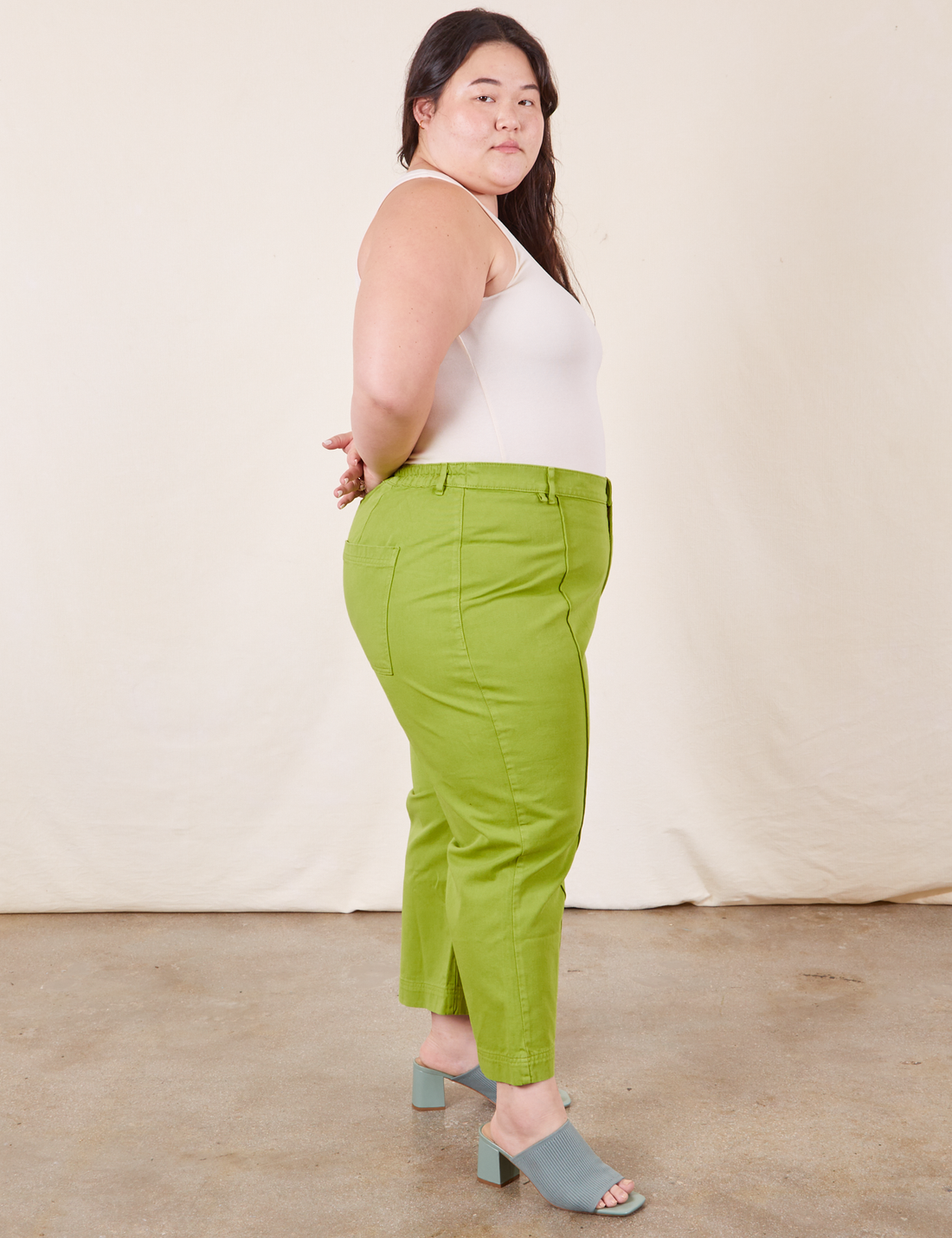 Side view of Western Pants in Gross Green paired with a vintage off-white Tank Top worn by Ashley