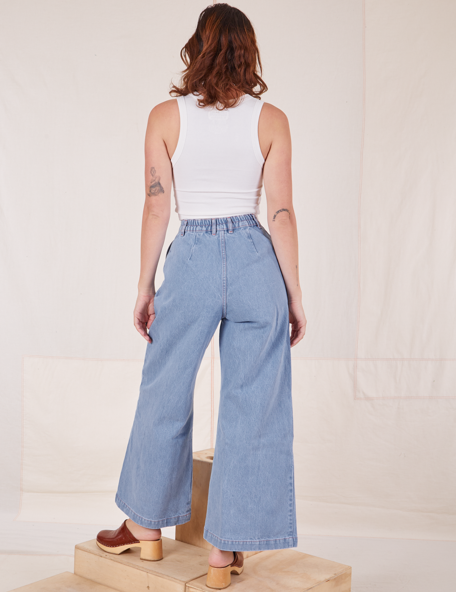 Back view of Indigo Wide Leg Trousers in Light Wash and vintage off-white Cropped Tank Top on Alex