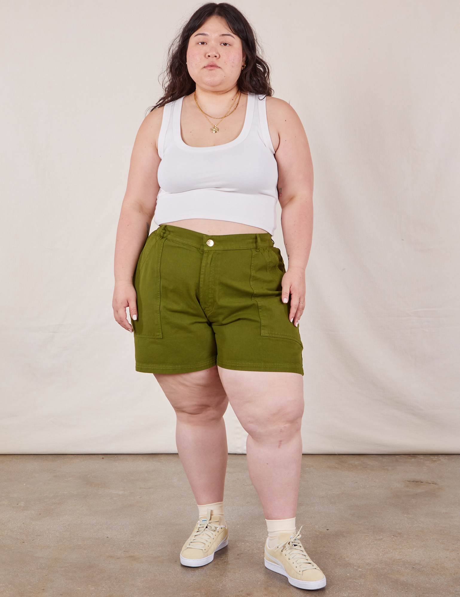 Ashley is 5’7” and wearing 1XL Classic Work Shorts in Summer Olive paired with a Cropped Tank Top in vintage tee off-white
