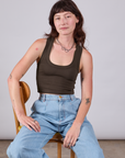 Alex is sitting in a chair wearing Cropped Tank Top in Espresso Brown paired with light wash Indigo Wide Leg Trousers