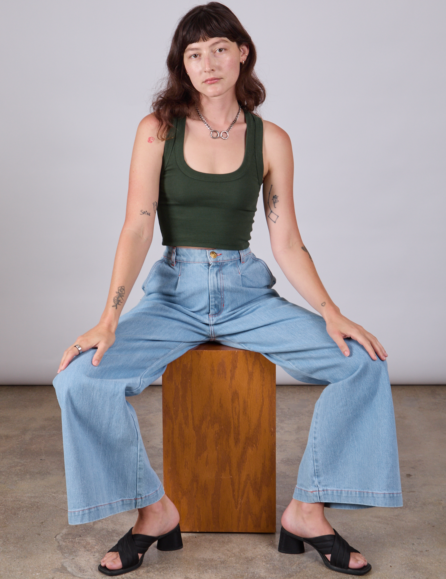 Alex is wearing Cropped Tank Top in Swamp Green paired with light wash Indigo Wide Leg Trousers