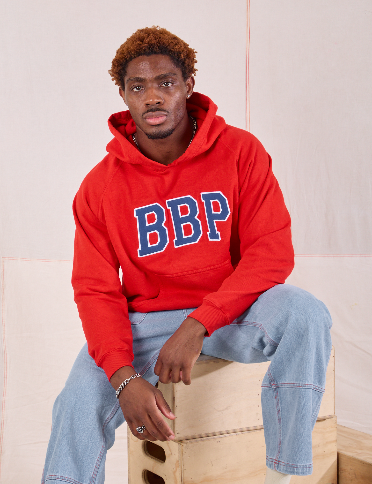 Issac is wearing Collegiate Hoodie in Mustang Red and light wash Carpenter Jeans