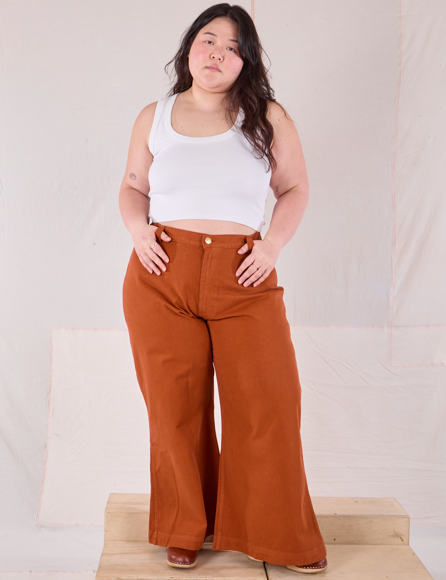 Ashley is 5&#39;7&quot; and wearing 1XL Bell Bottoms in Burnt Terracotta paired with a Cropped Tank in vintage tee off-white