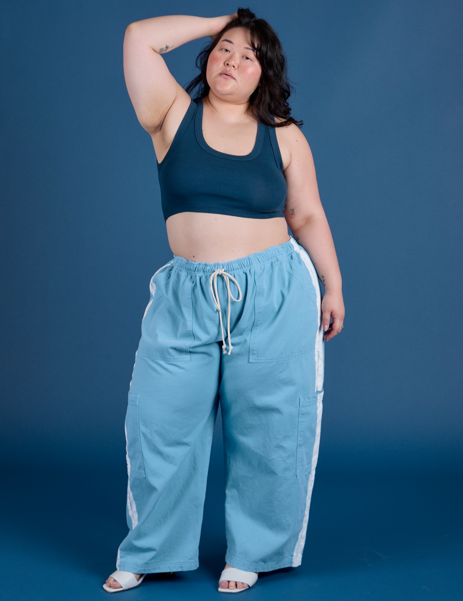 Ashley is 5’7” and wearing 1XL Painted Drop Pocket Cargo Pants in Baby Blue paired with lagoon Mini Tank