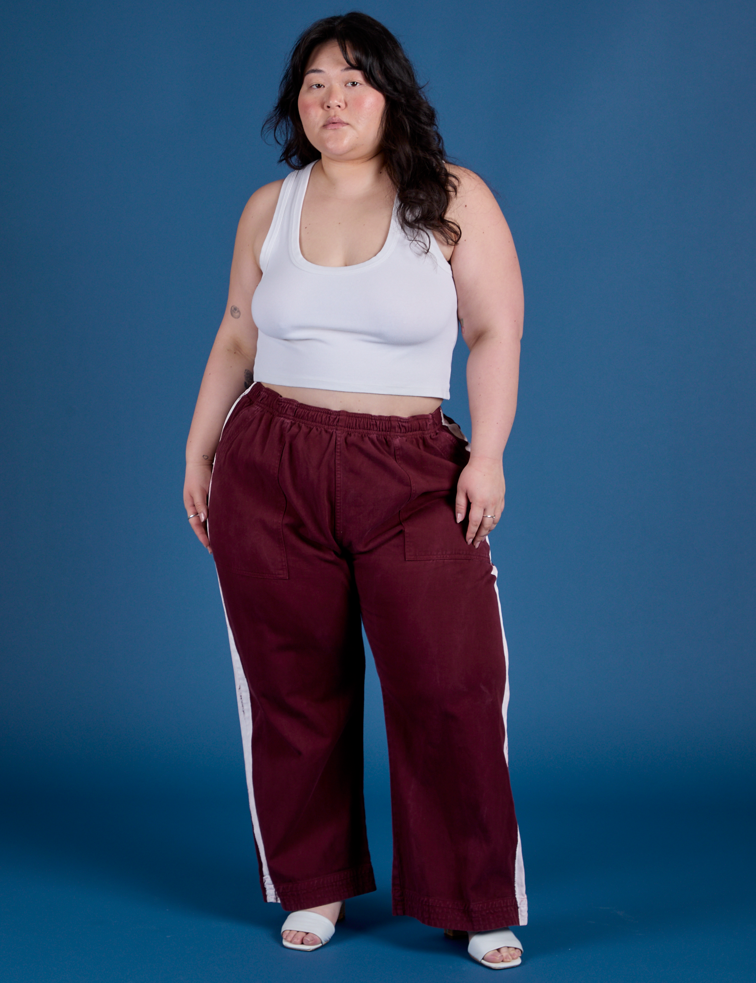 Ashley is 5’7” and wearing 1XL Painted Action Pants in Red Wine paired with vintage tee white Cropped Tank