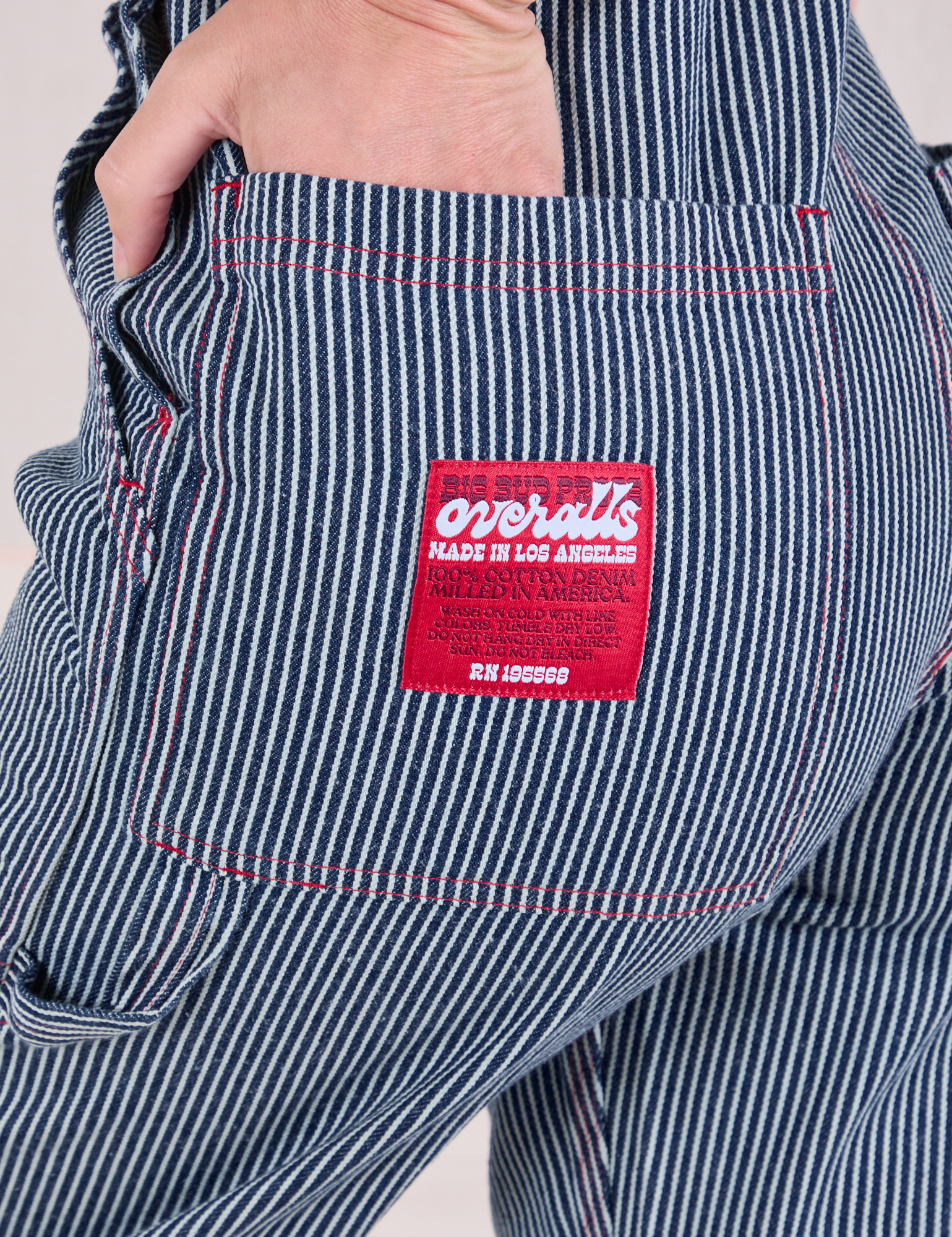 Close up of Alex&#39;s hand in the back pocket of Carpenter Overalls in Railroad