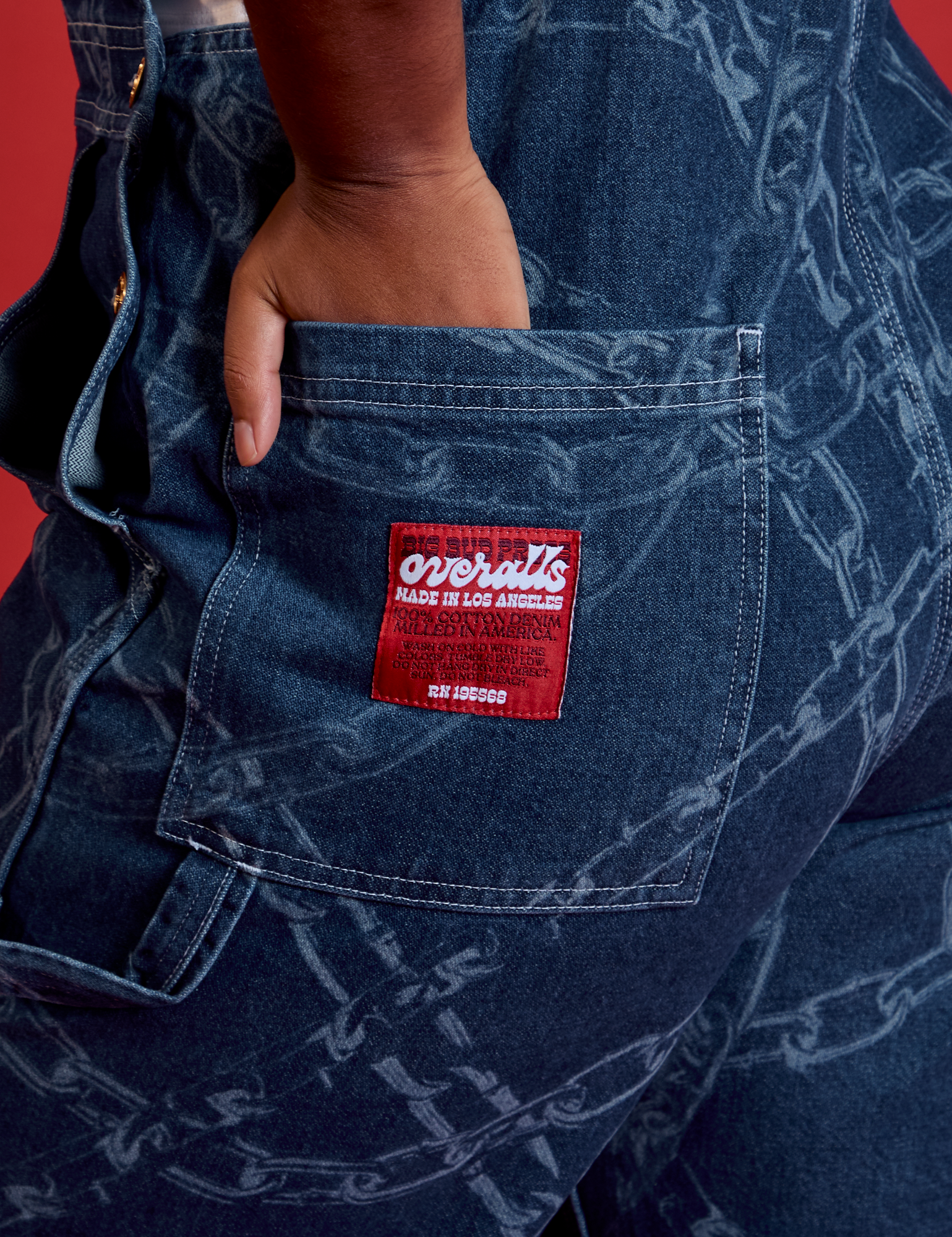 Meghna has her hand in the back pocket of Carpenter Overalls in Chain Link