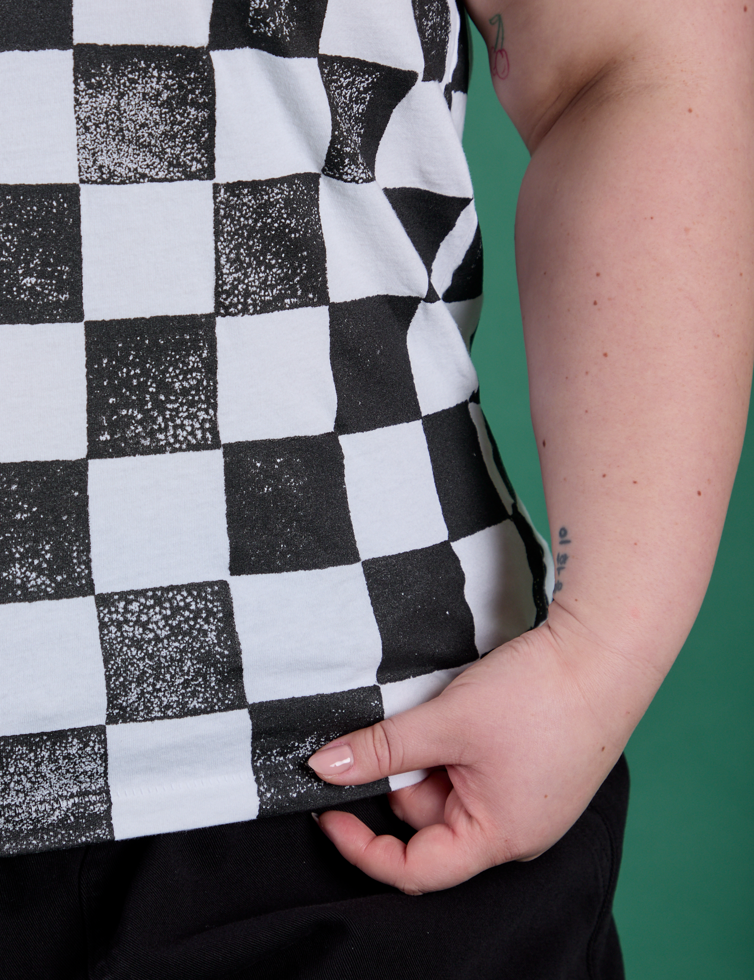 Checker Organic Tee in Black bottom close up with Ashley holding the hem