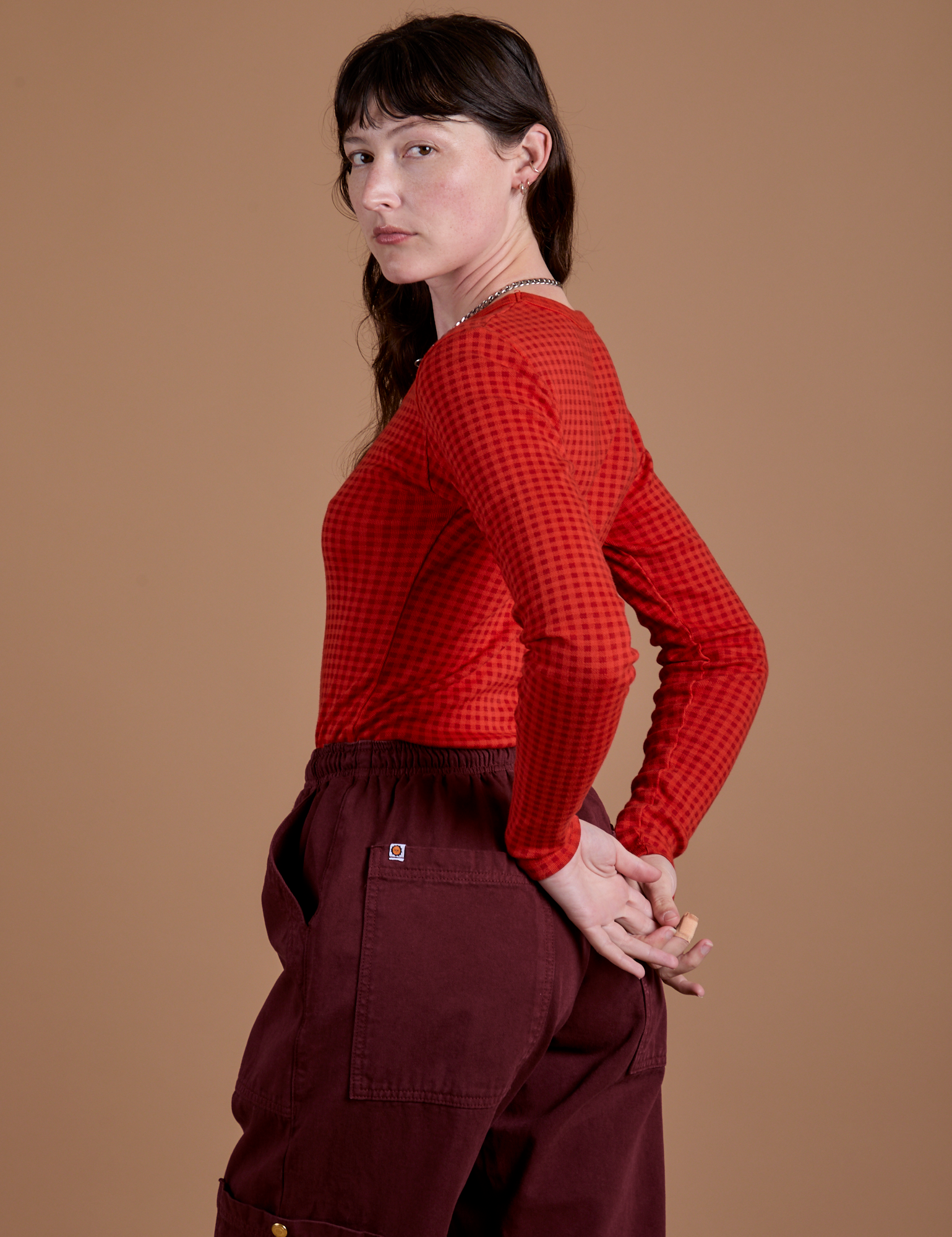 Angled back view of Gingham Long Sleeve Baby Tee in Mustang Red on Alex