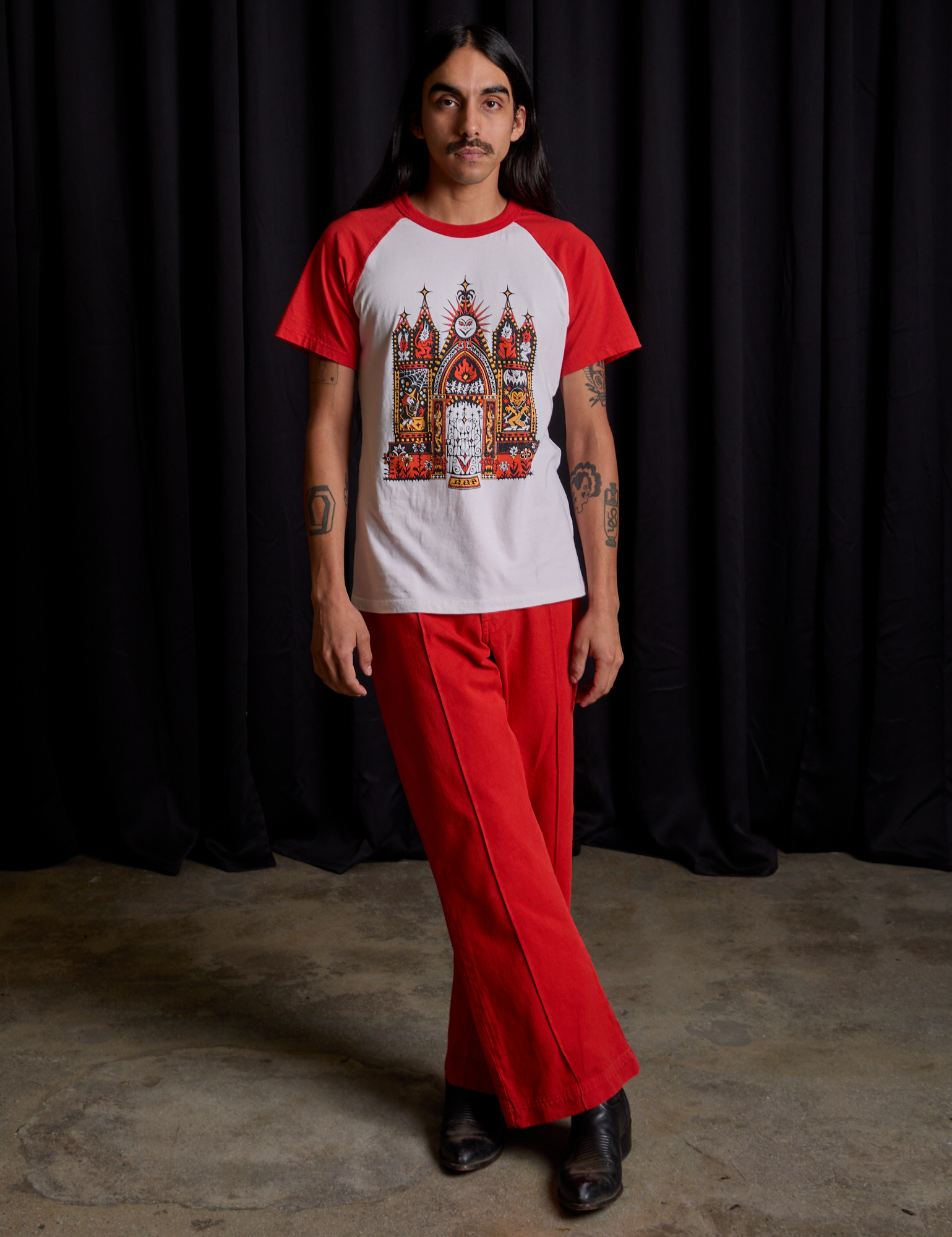 Anthony is wearing Short Sleeve Raglan Tee in Gates of Hell and mustang red Western Pants