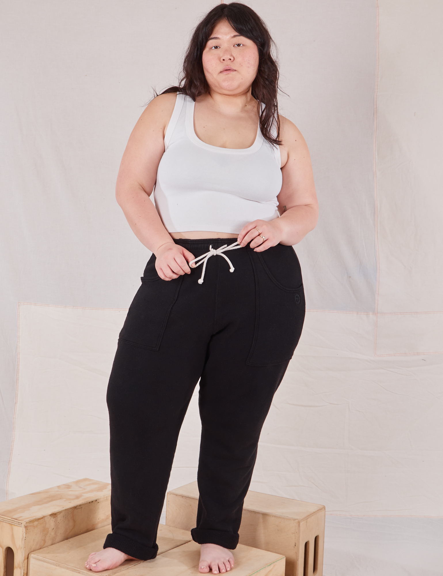 Ashley is 5&#39;7&quot; and wearing L Rolled Cuff Sweat Pants in Basic Black paired with vintage off-white Cropped Tank