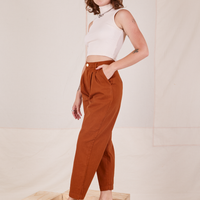 Angled view of Heavyweight Trousers in Burnt Terracotta and vintage off-white Sleeveless Turtleneck worn by Alex
