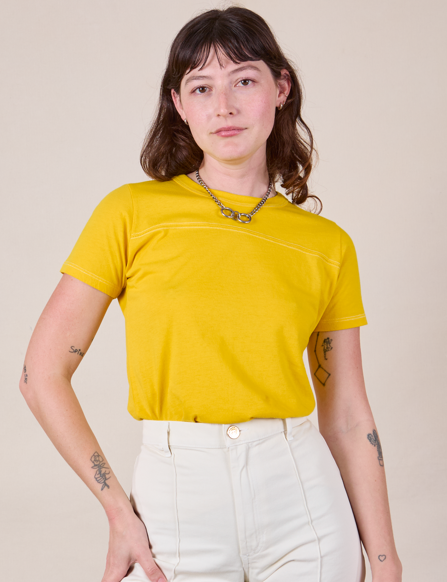 Alex is wearing JV Tee in Golden Yellow tucked into vintage tee off-white Western Pants