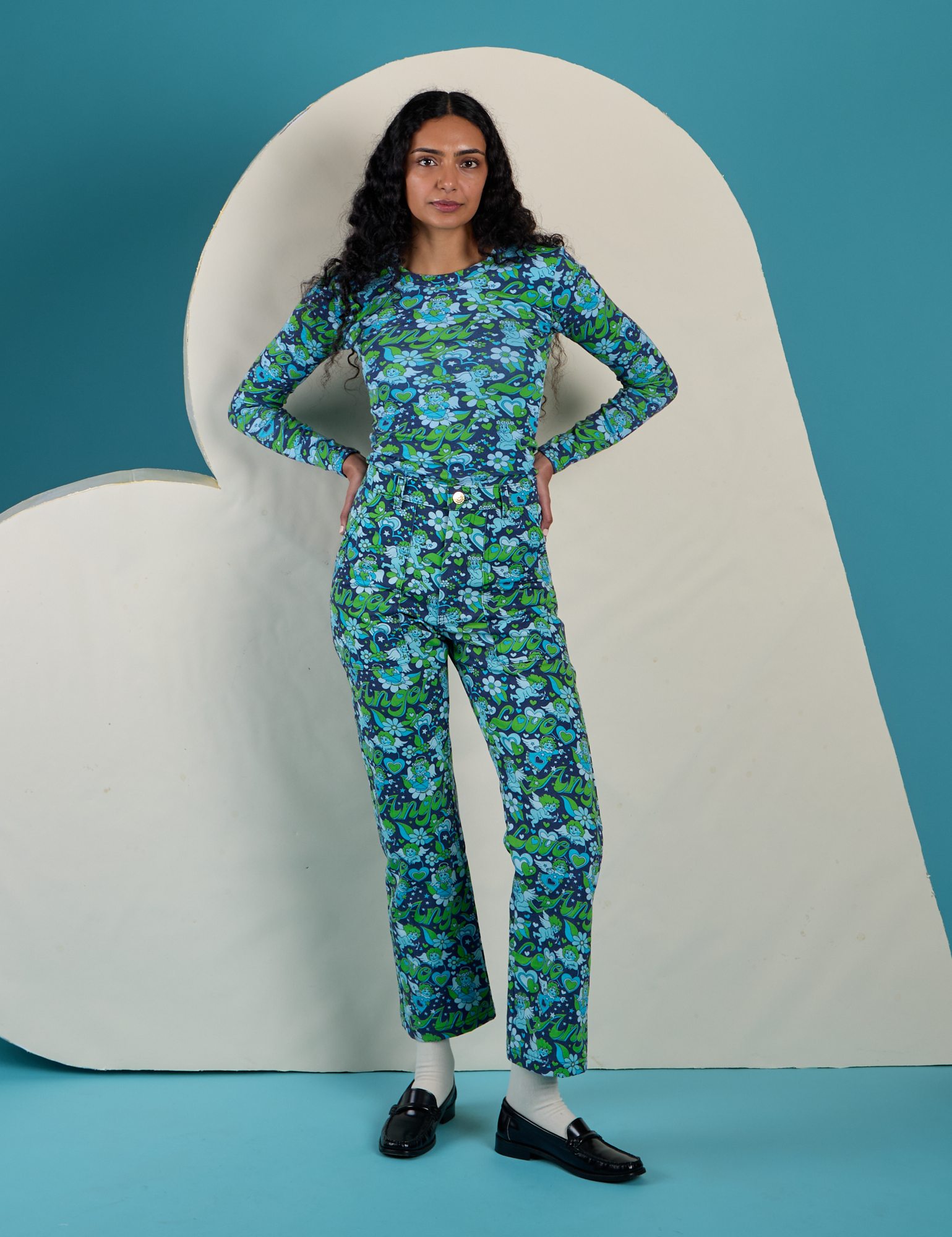 Shahana is 5’10 and wearing P Long Sleeve Baby Tee in Angel Print paired with matching Work Pants