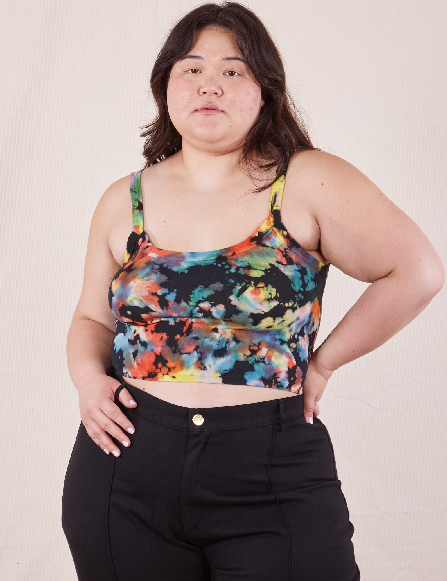 Ashley is 5&#39;7&quot; and wearing L Cropped Cami in Rainbow Magic Waters paired with black Western Pants. She has her left thumb through one of the belt loops.