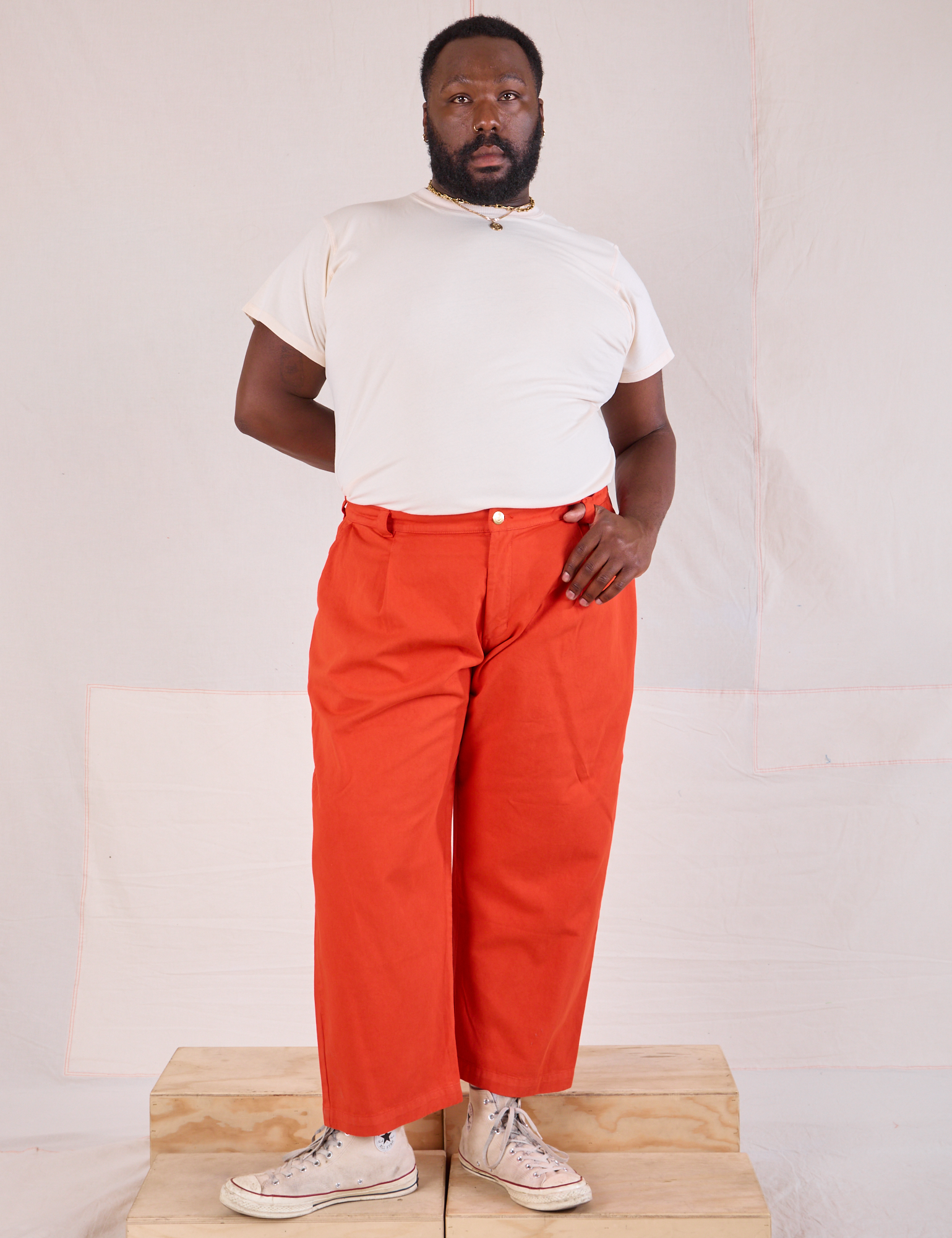 Elijah is 6&#39;3&quot; and wearing 1XL Mid-Rise Pleated Trousers in Chili Red paired with Organic Vintage Tee in Vintage Tee Off-White