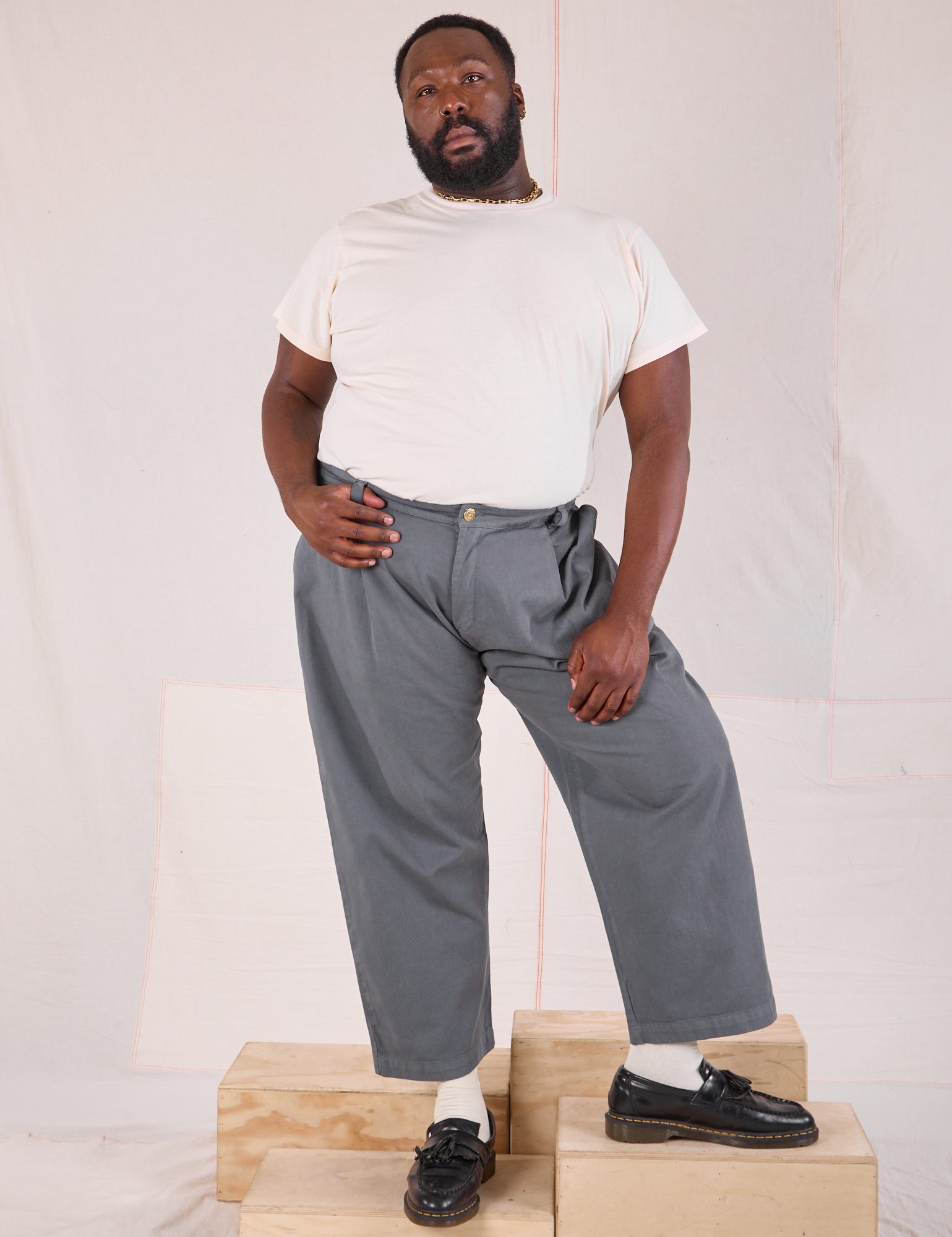 Elijah is 6&#39;3&quot; and wearing 1XL Mid-Rise Pleated Trousers in Slate Grey paired with an Organic Vintage Tee in vintage tee off-white