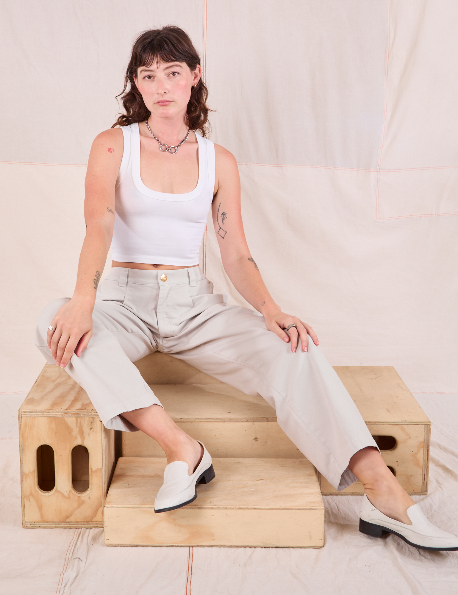 Alex is wearing Mid-Rise Pleated Trousers in Stone White and Cropped Tank in vintage tee off-white