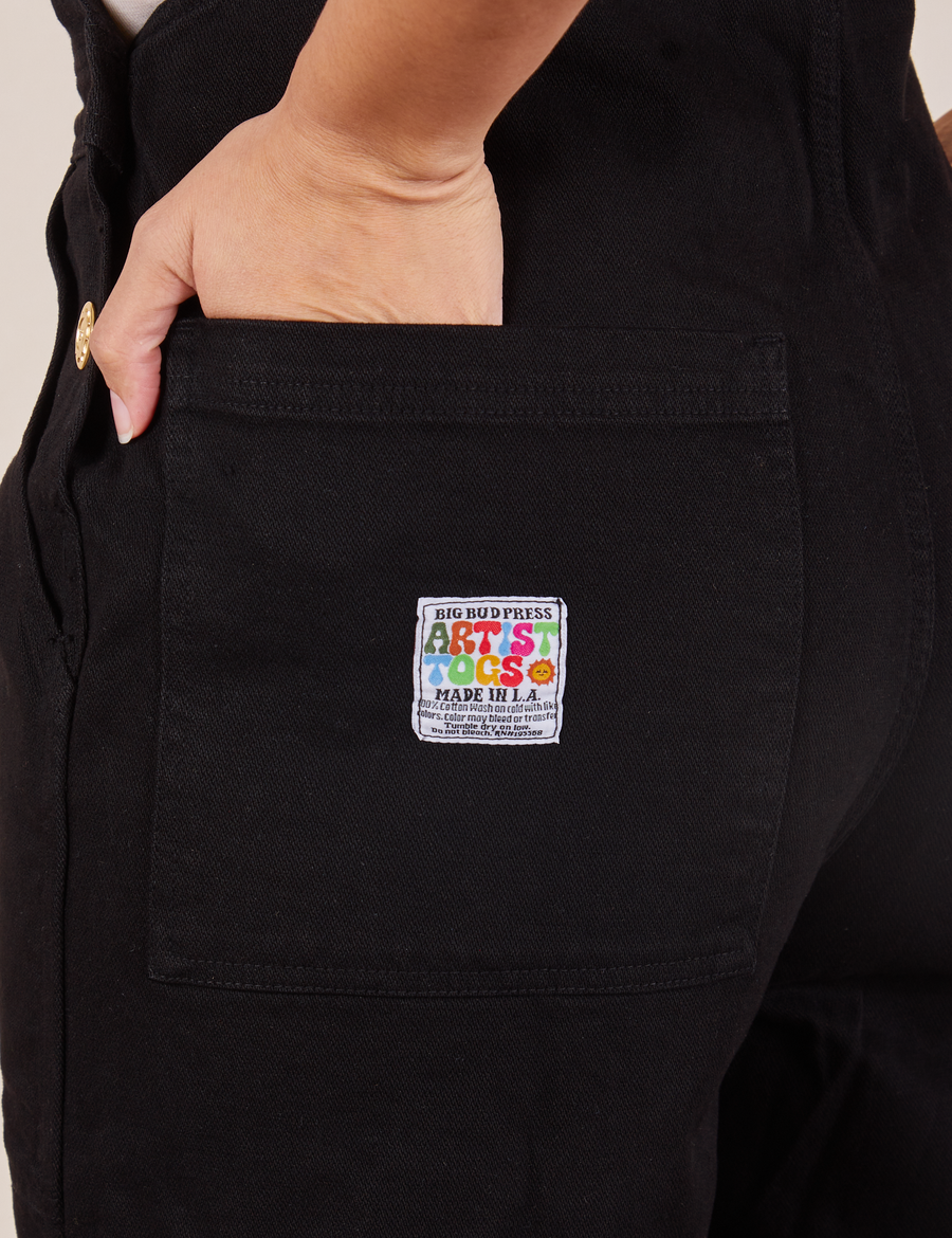 Back pocket close up of Original Overalls in Mono Black. Tiara has her hand in the pocket.