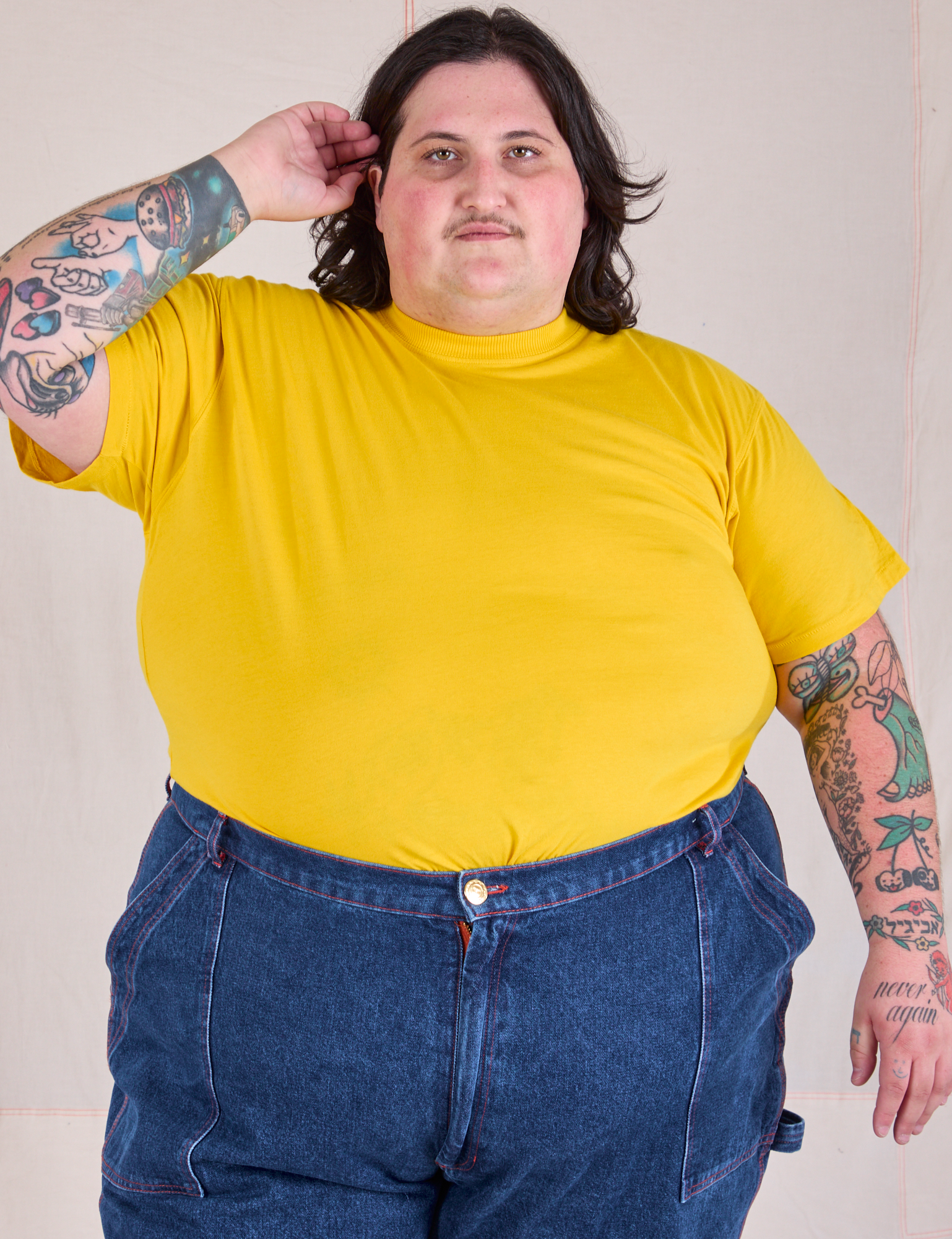 Sam is wearing Organic Vintage Tee in Golden Yellow tucked into dark wash Carpenter Jeans