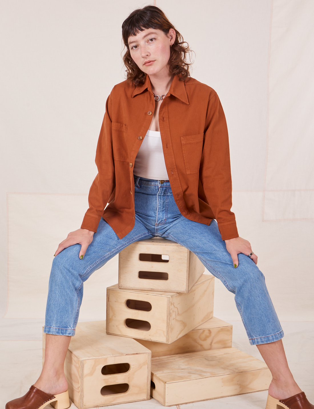 Alex is wearing Oversize Overshirt in Burnt Terracotta, vintage off-white Cropped Tank Top and light wash Frontier Jeans