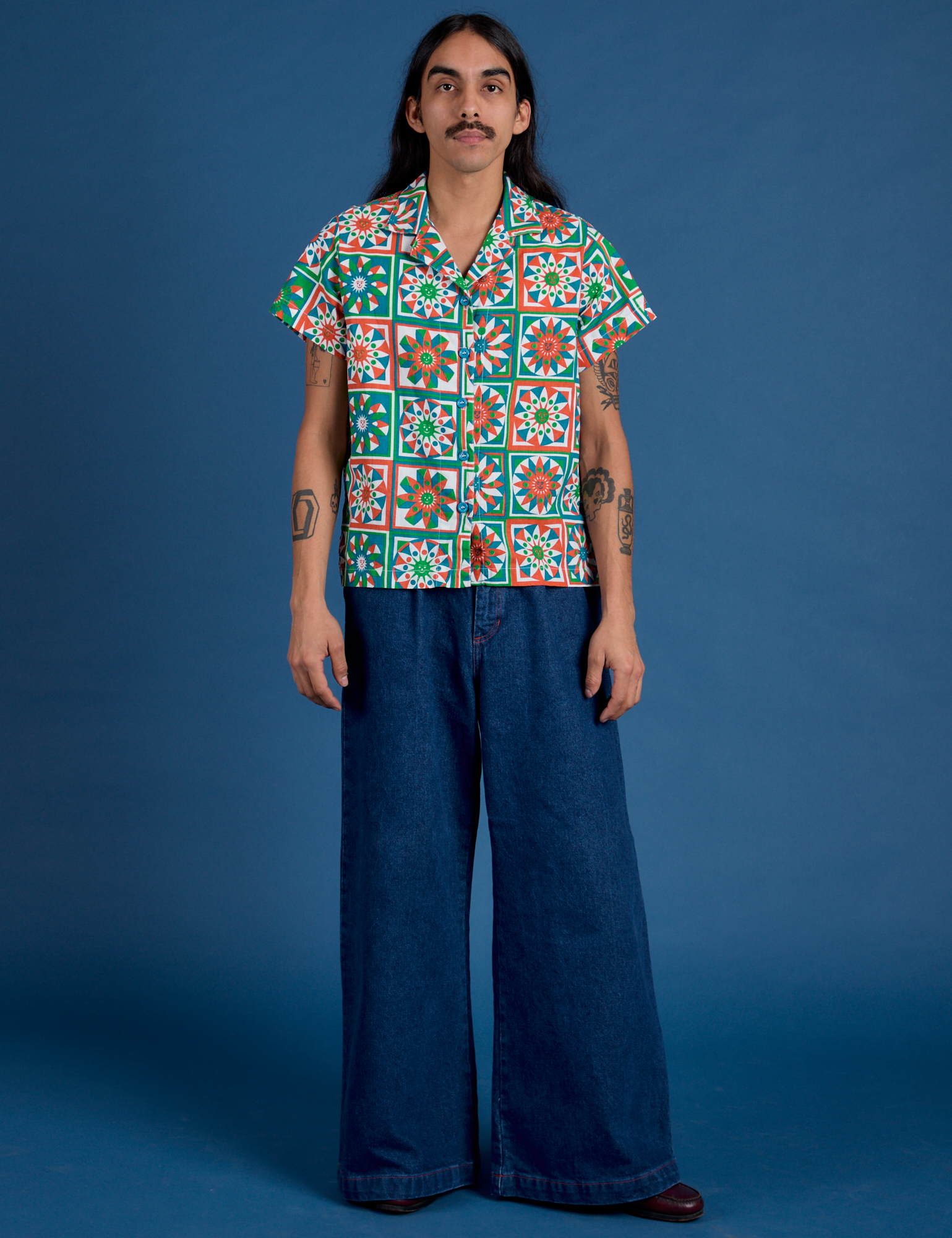 Anthony is wearing Quilt Print Pantry Button-Up and Indigo Wide Leg Trousers in Dark Wash