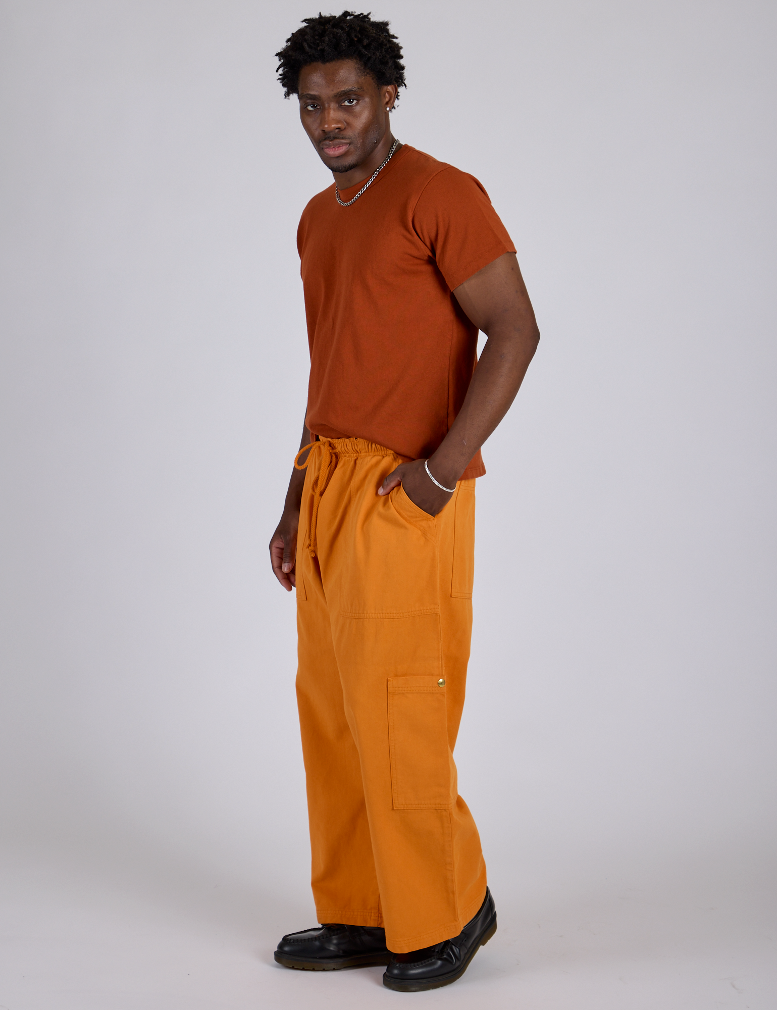 Side view of Drop Pocket Cargo Pants in Creamsicle Orange and burnt terracotta Organic Vintage Tee on Isaac