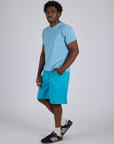 Angled front view of Longline Work Shorts in Hawaiian Blue and baby blue Organic Vintage Tee on Isaac