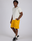 Angled front view of Longline Work Shorts in Sunshine Yellow and Burly Tee in Vintage Tee White on Isaac