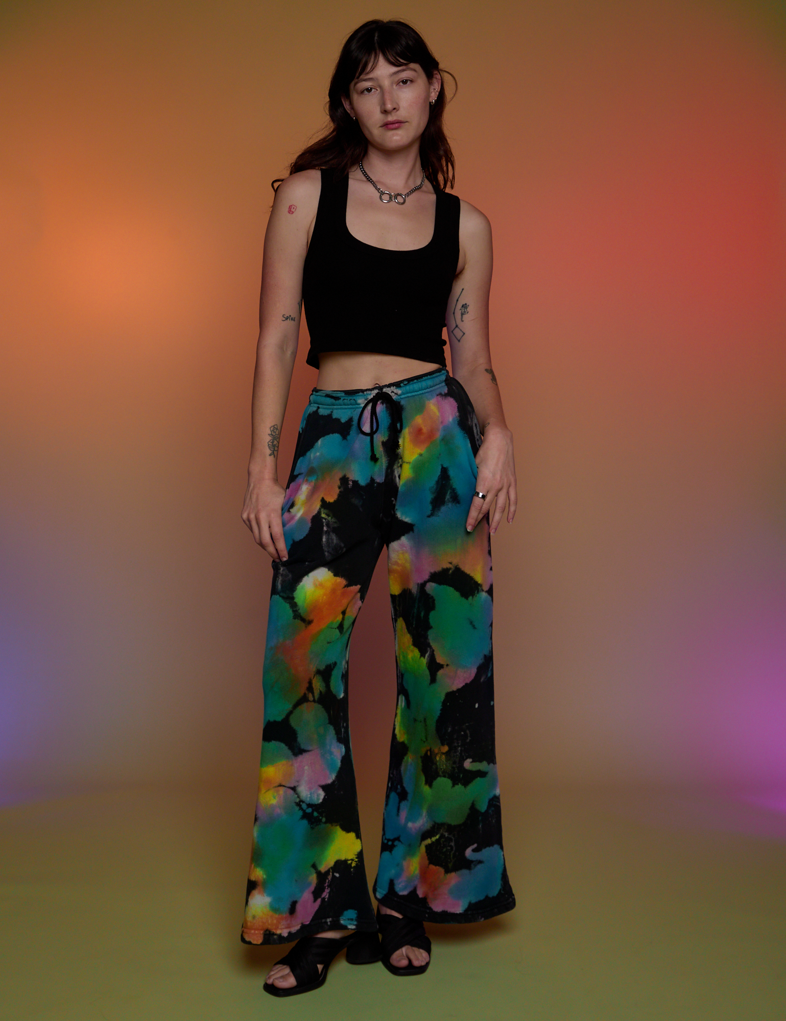 Alex is 5’8” and wearing P Tie Dyed Wide Leg Sweat Pants paired with a black Cropped Tank