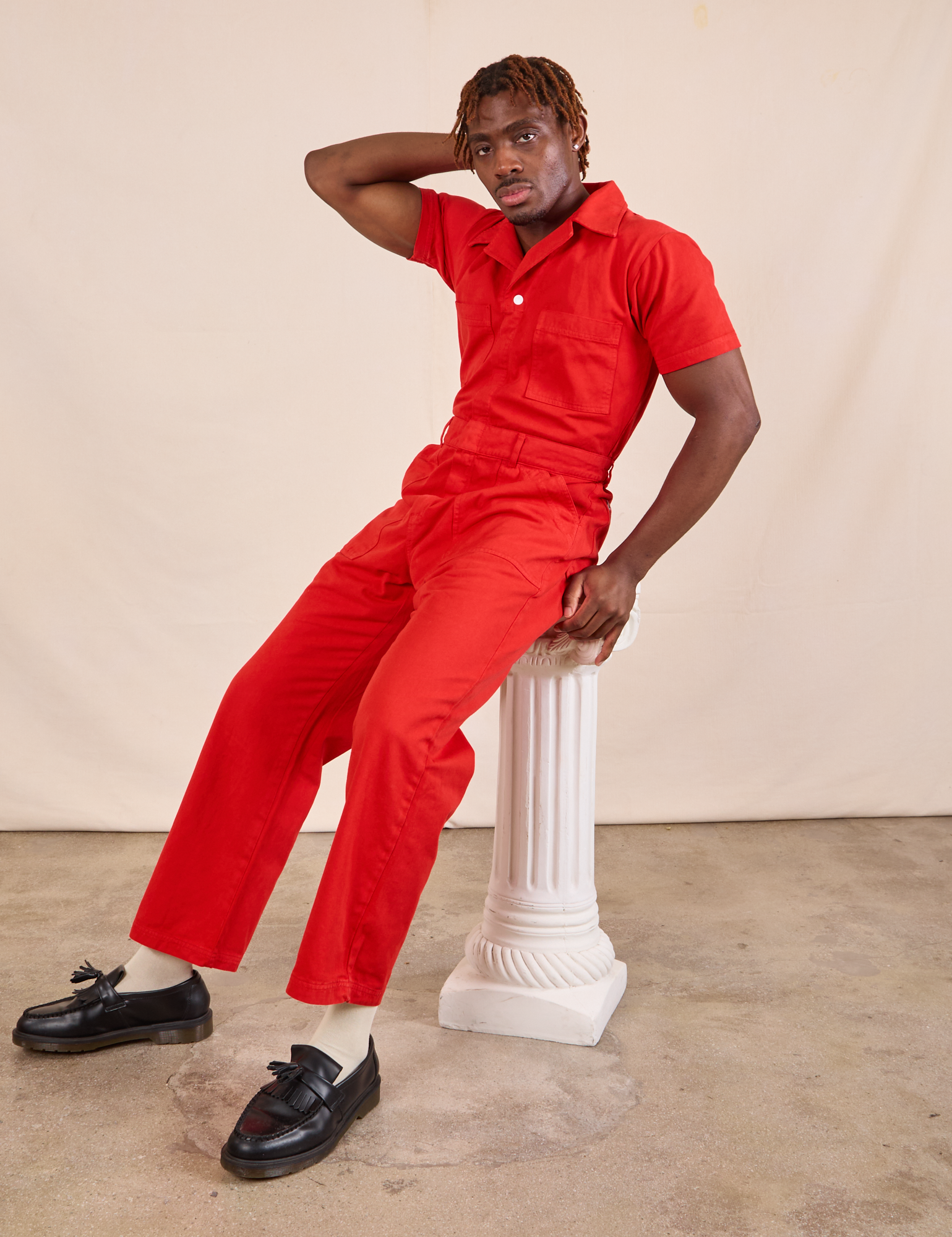 Issac is wearing Short Sleeve Jumpsuit in Mustang Red