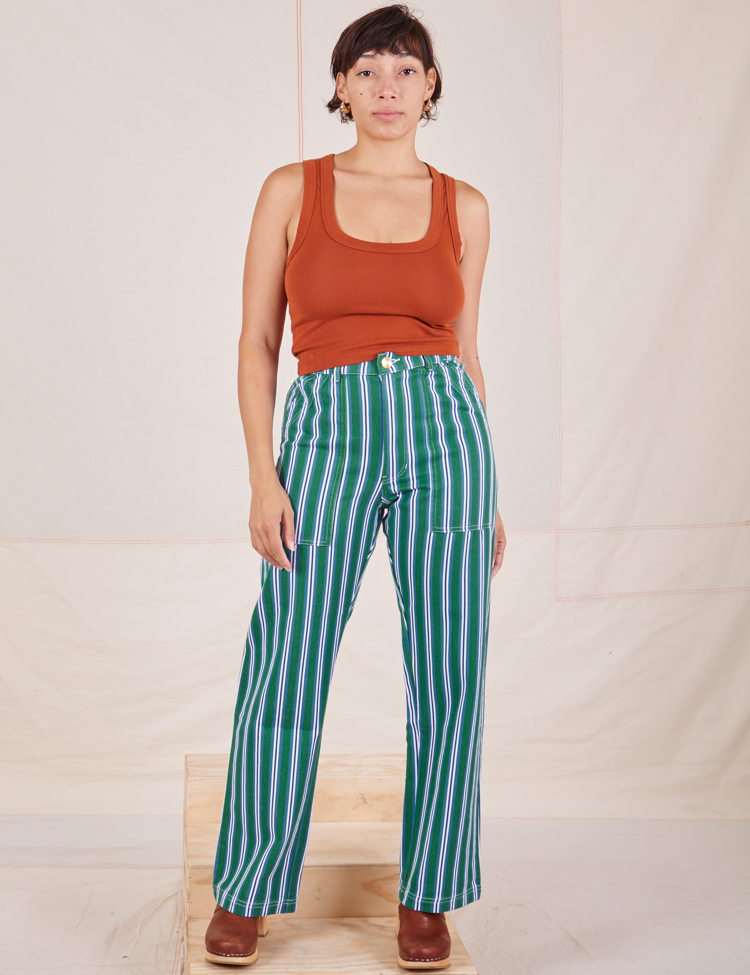 Tiara is 5&#39;4&quot; and wearing S Stripe Work Pants in Green paired with burnt terracotta Cropped Tank