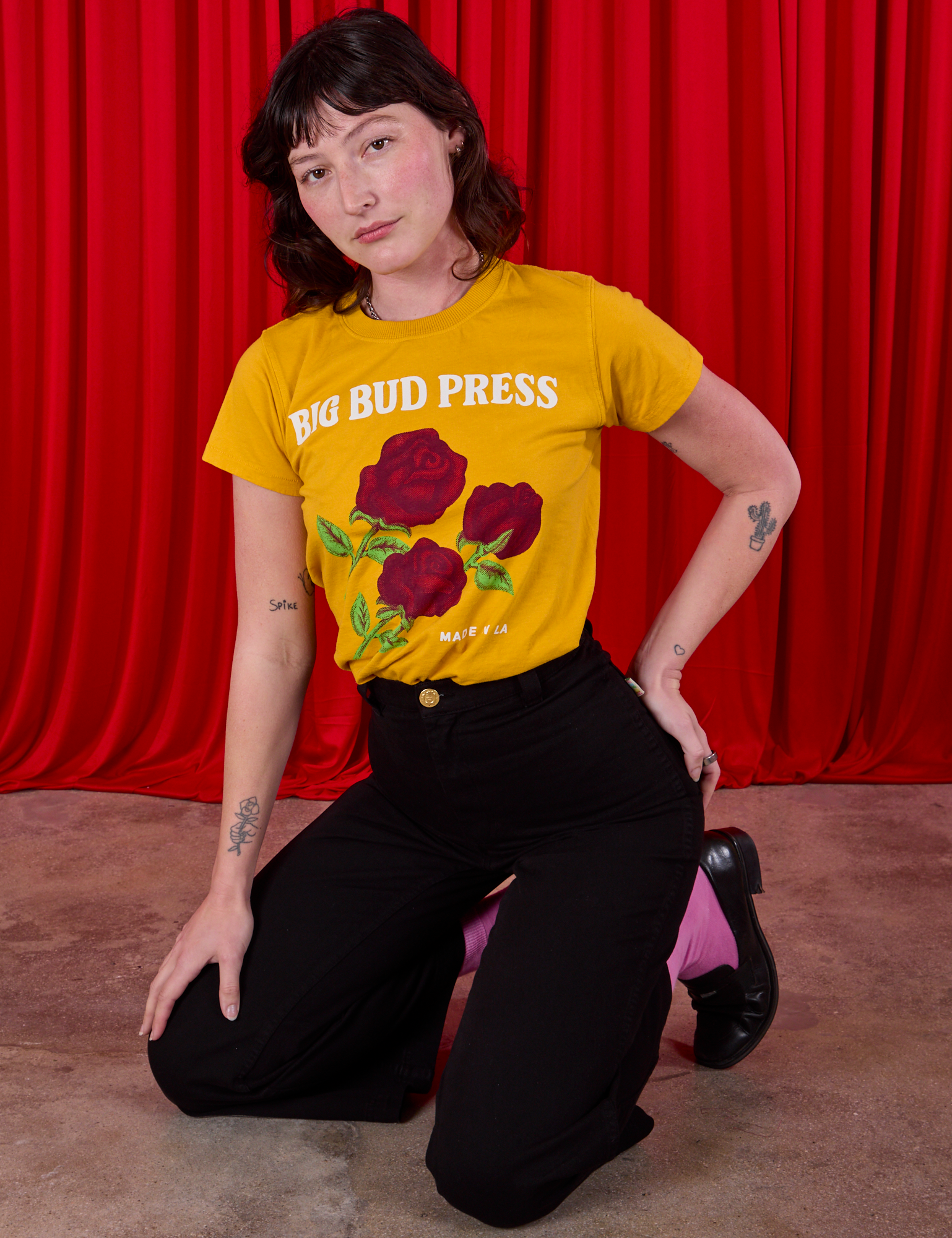 Alex is wearing 3 Roses Organic Tee tucked into black Bell Bottoms