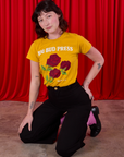 Alex is wearing 3 Roses Organic Tee tucked into black Bell Bottoms