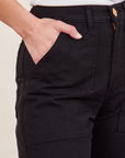 Front pocket close up ofWork Pants in Basic Black. Soraya has her hand in the pocket.