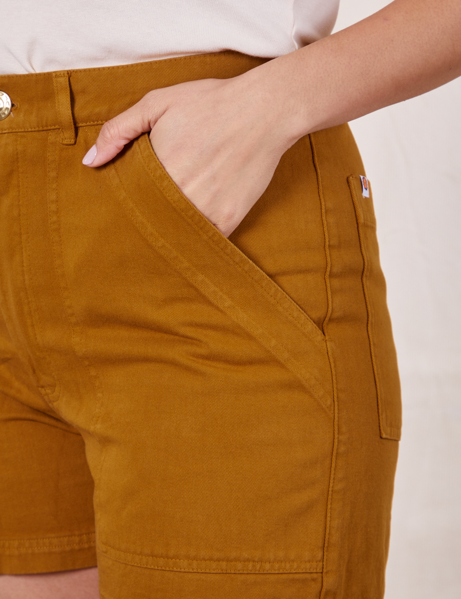 Classic Work Shorts in Spicy Mustard front close up with Tiara's hand in pocket.