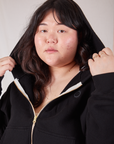 Cropped Zip Hoodie in Basic Black front close up. Ashley is wearing the hood over her head