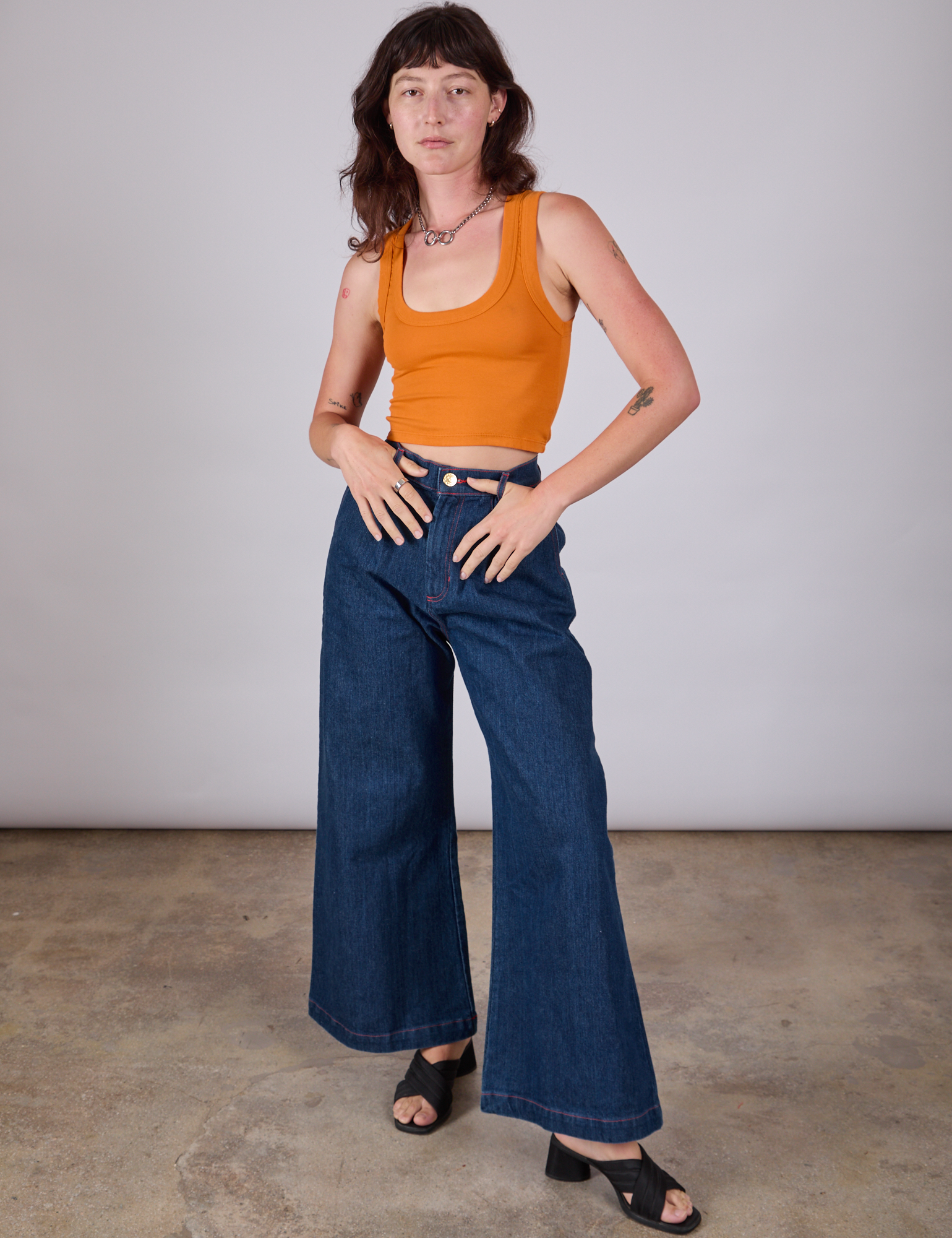 Alex is wearing Cropped Tank Top in Creamsicle Orange paired with dark wash Indigo Wide Leg Trousers