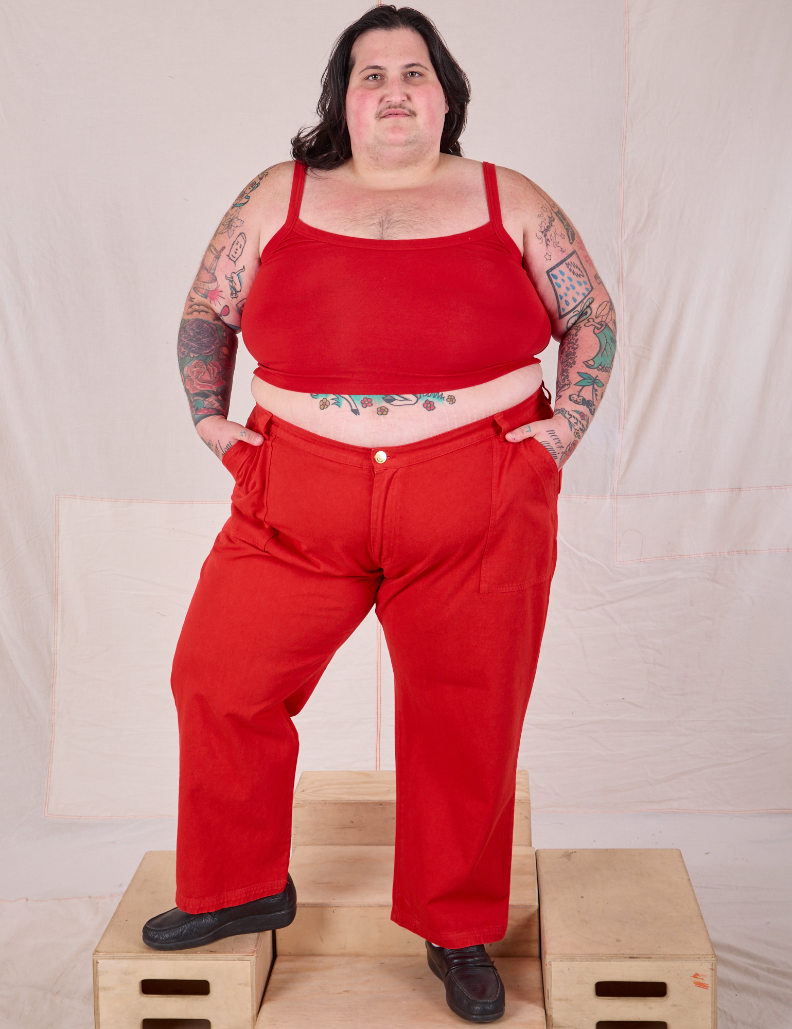 Sam is 5’10” and wearing 4XL Mid-Rise Work Pants in Mustang Red paired with a matching Cropped Cami