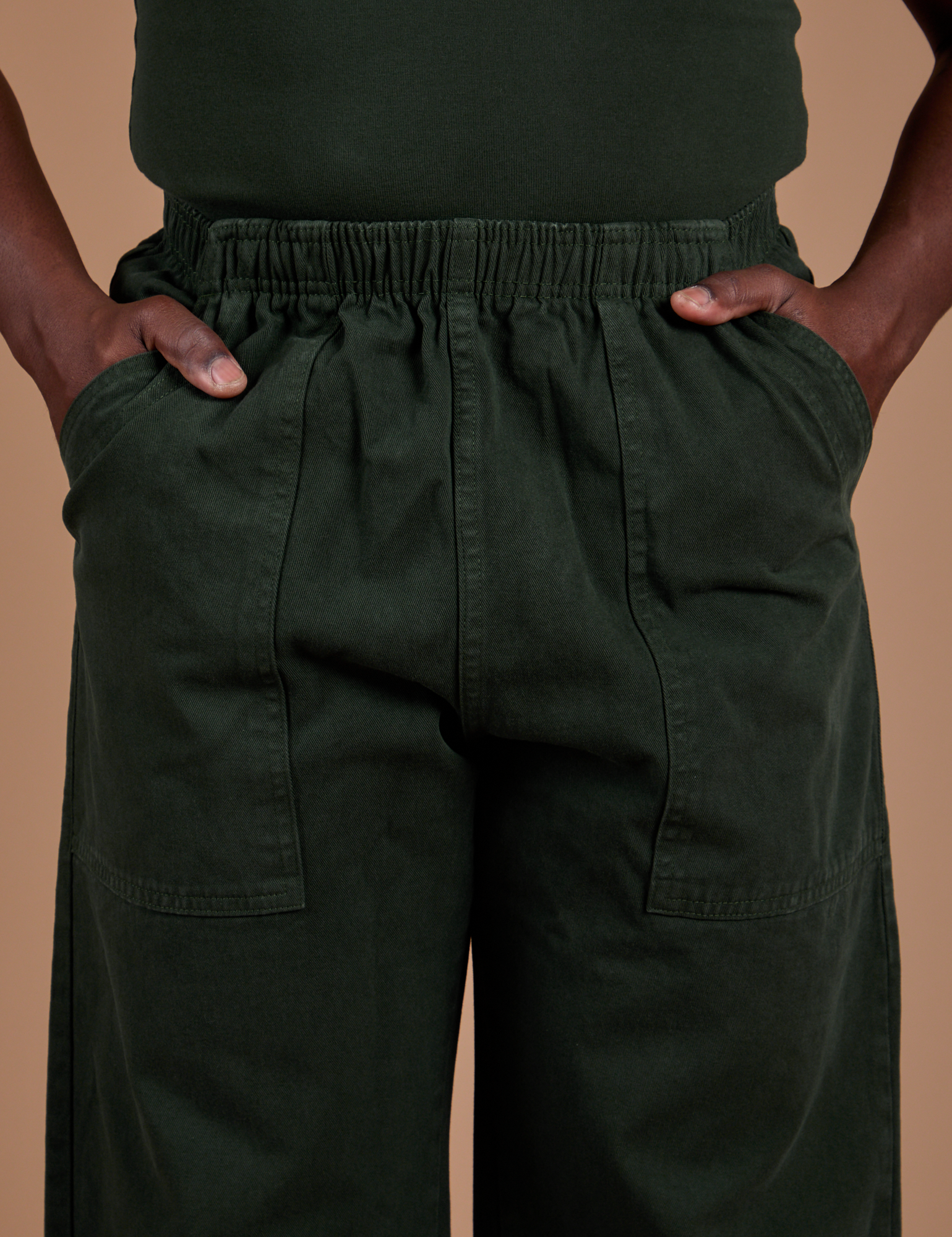Action Pants in Swamp Green front close up with Demi's hands in both front pockets