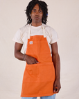 Jerrod is wearing the Full Denim Apron in Construction Orange