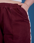 Close up of Ashley's hand in the front pocket of Painted Action Pants in Red Wine
