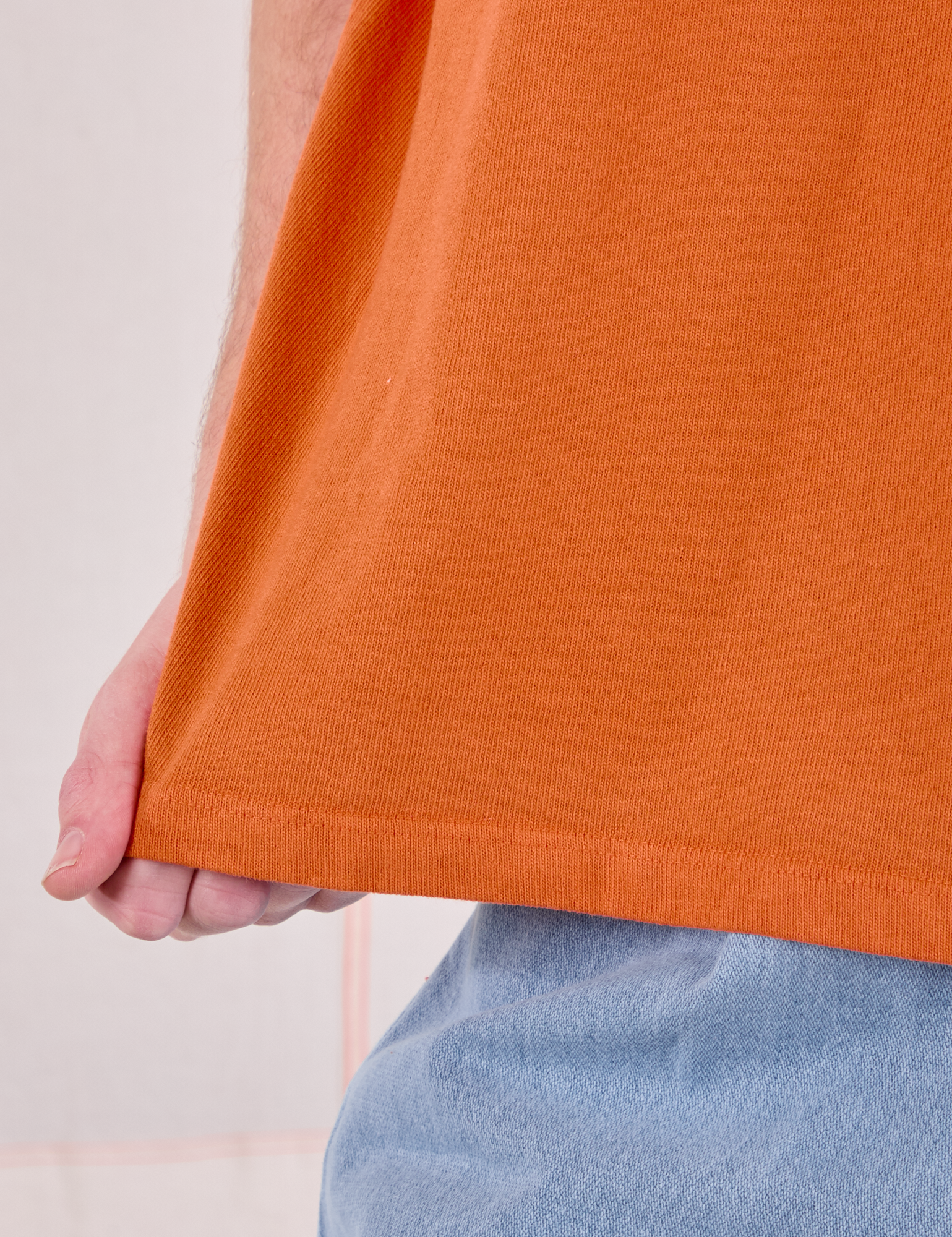 Burly Tee in Construction Orange bottom hem close up on Quinn