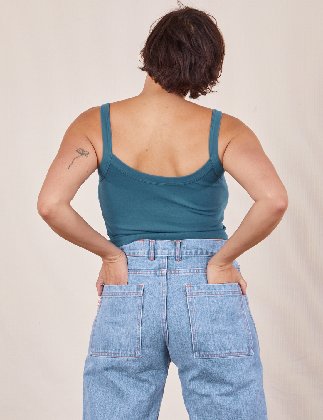 Back view of Cropped Cami in Marine Blue and light wash Sailor Jeans worn by Tiara. She has her hands in both back pant pockets.