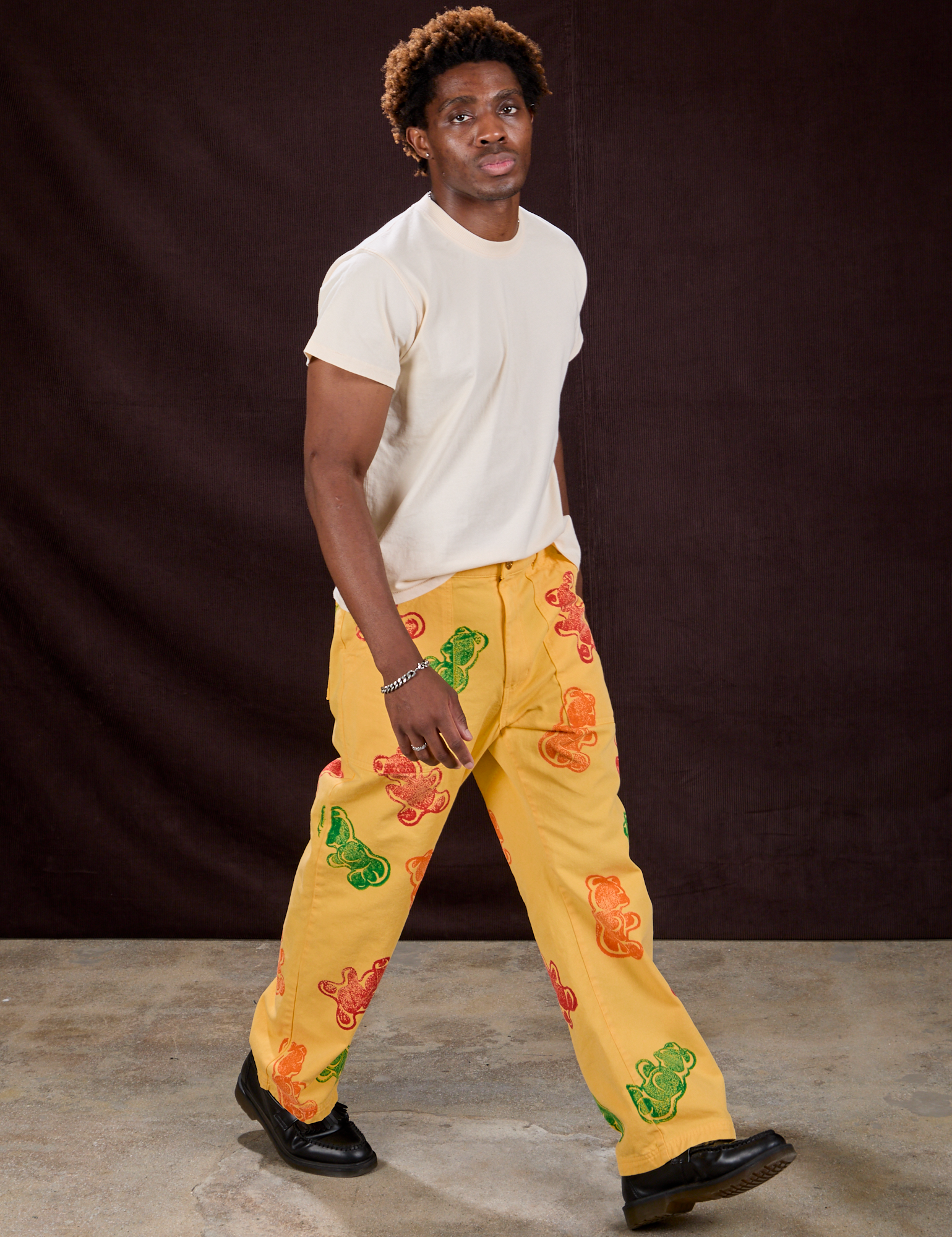 Angled front view of Gummy Bear Paintstamped Work Pants in Butter Yellow and Organic Vintage Tee in Vintage Off-White